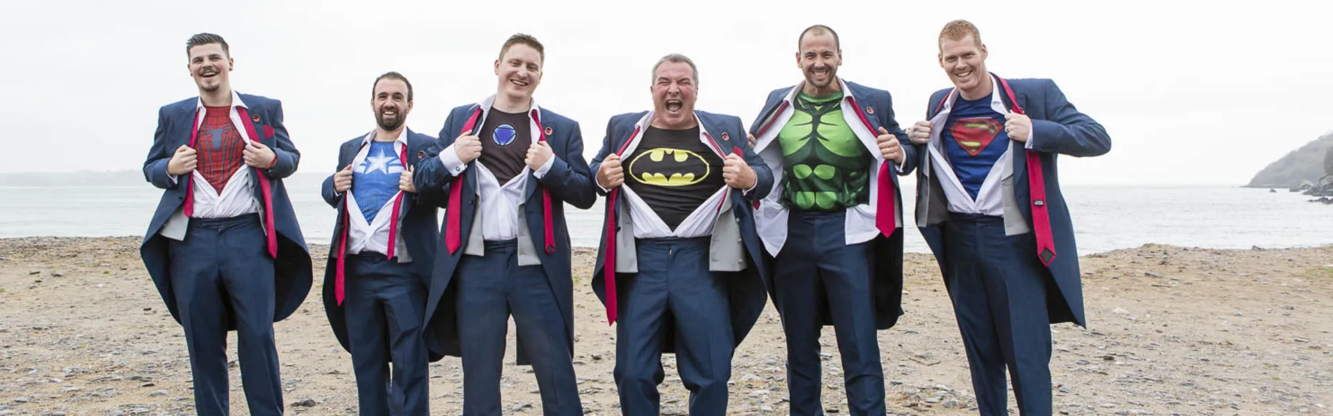 Groomsmen reveal superhero t-shirts under their wedding attire, adding a playful touch to the celebration