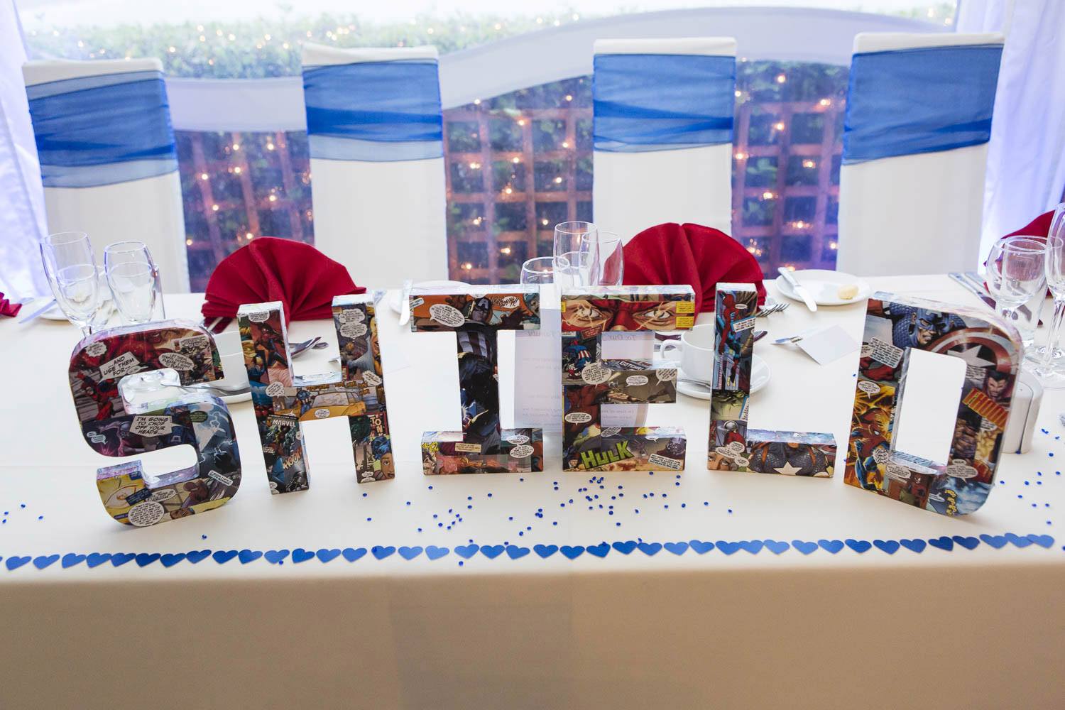 Guests marvel at the creative table settings, featuring superhero-themed place cards and favors