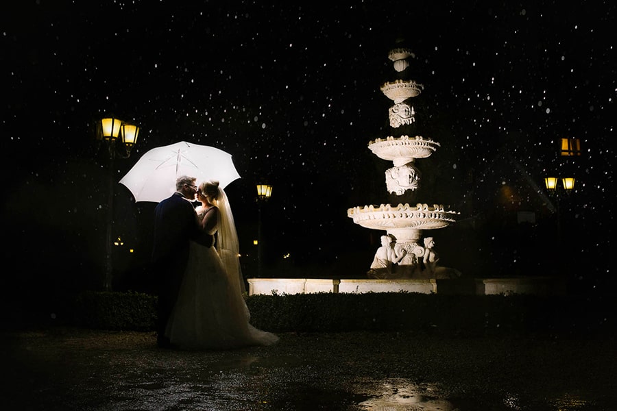 Newly wed dancing in the rain in front of fountain at night time, Berwick Lodge