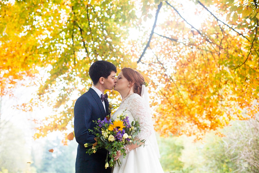 Newly weds kiss under Autumn leaves at Caldicot Castle